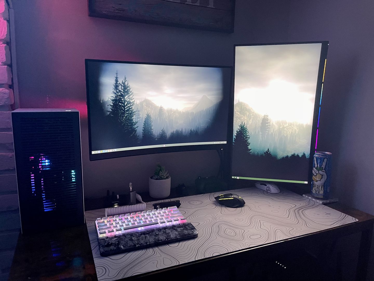 Customer gaming setup with a custom printed desk mat under a white keyboard and mouse, matching the wallpaper on two monitors