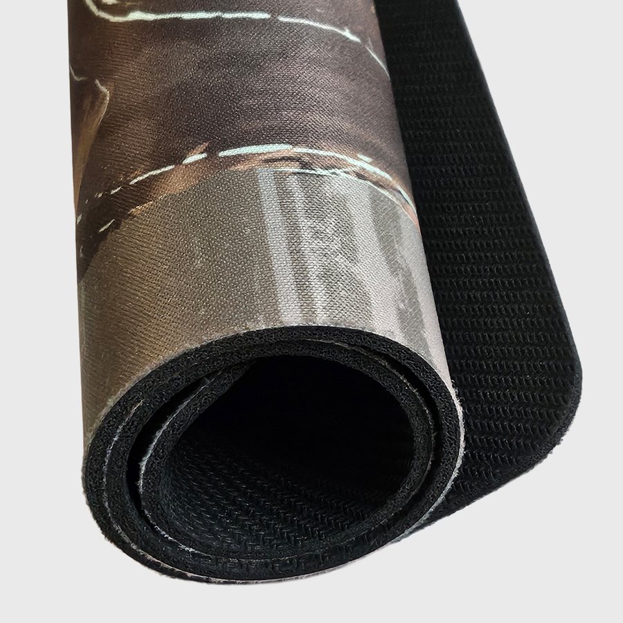 Custom desk mat rolled up showing the printed cloth top and black rubber backing